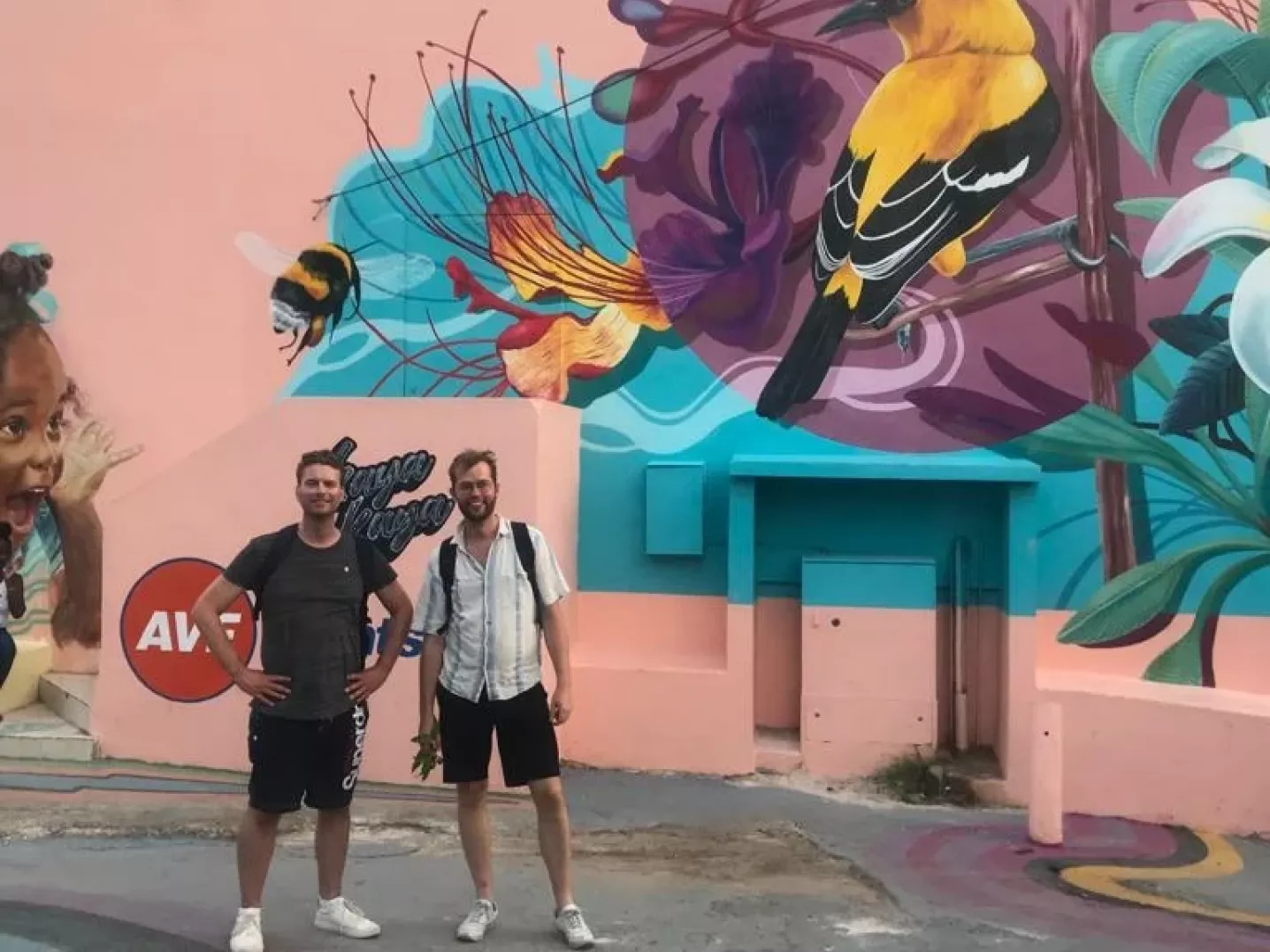 Two men standing in front of a colourful wall painting in Willemstad, Curaçao