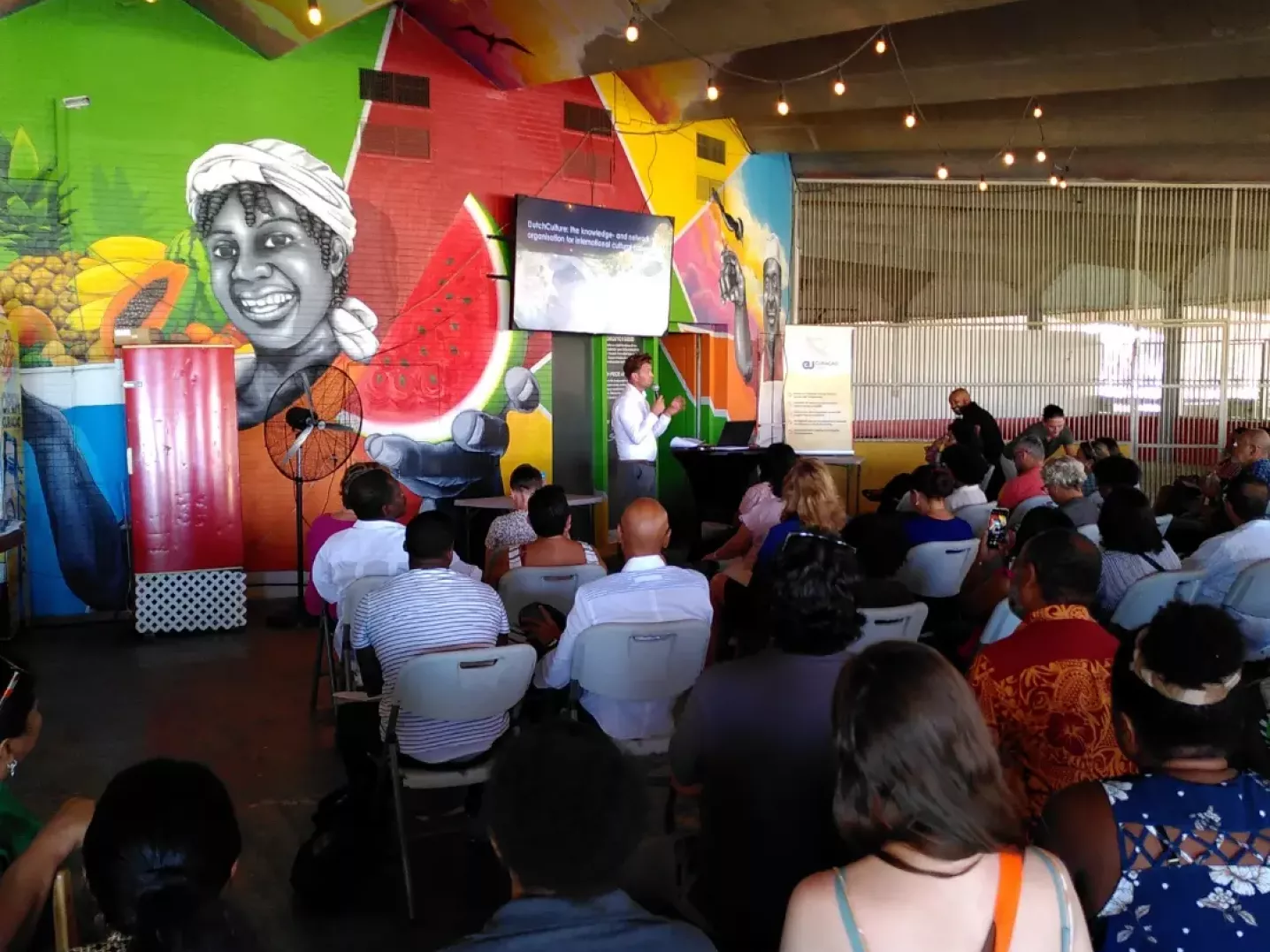 audience looks at creative europe presentation in colourfol outdoor space in Curaçao