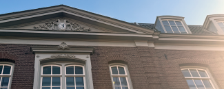 Old building with a frieze on the facade, high windows and a blue sky