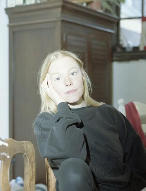 A woman dressed in black sitting with her head in her hand 