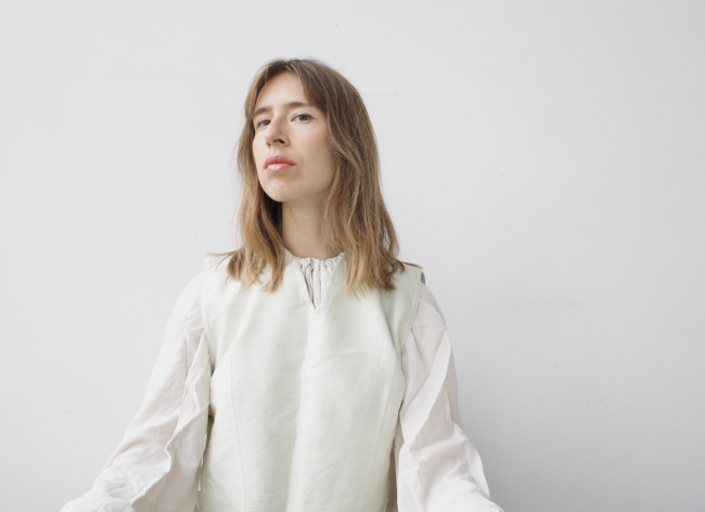 A woman dressed in white standing in front of a white wall