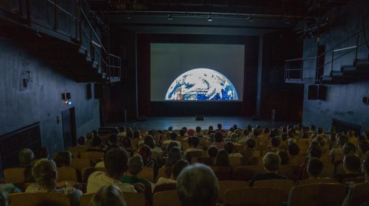 Volle bioscoop met aardbol op scherm