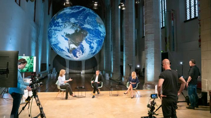 Drie sprekers worden gefilmd in een kerk