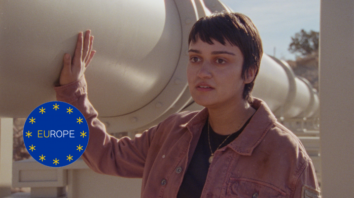 Film still of How to Blow Up a Pipeline. Woman holding her right hand against a big white pipe.