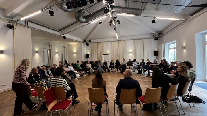 mensen zittend in een kring in een grote zaal